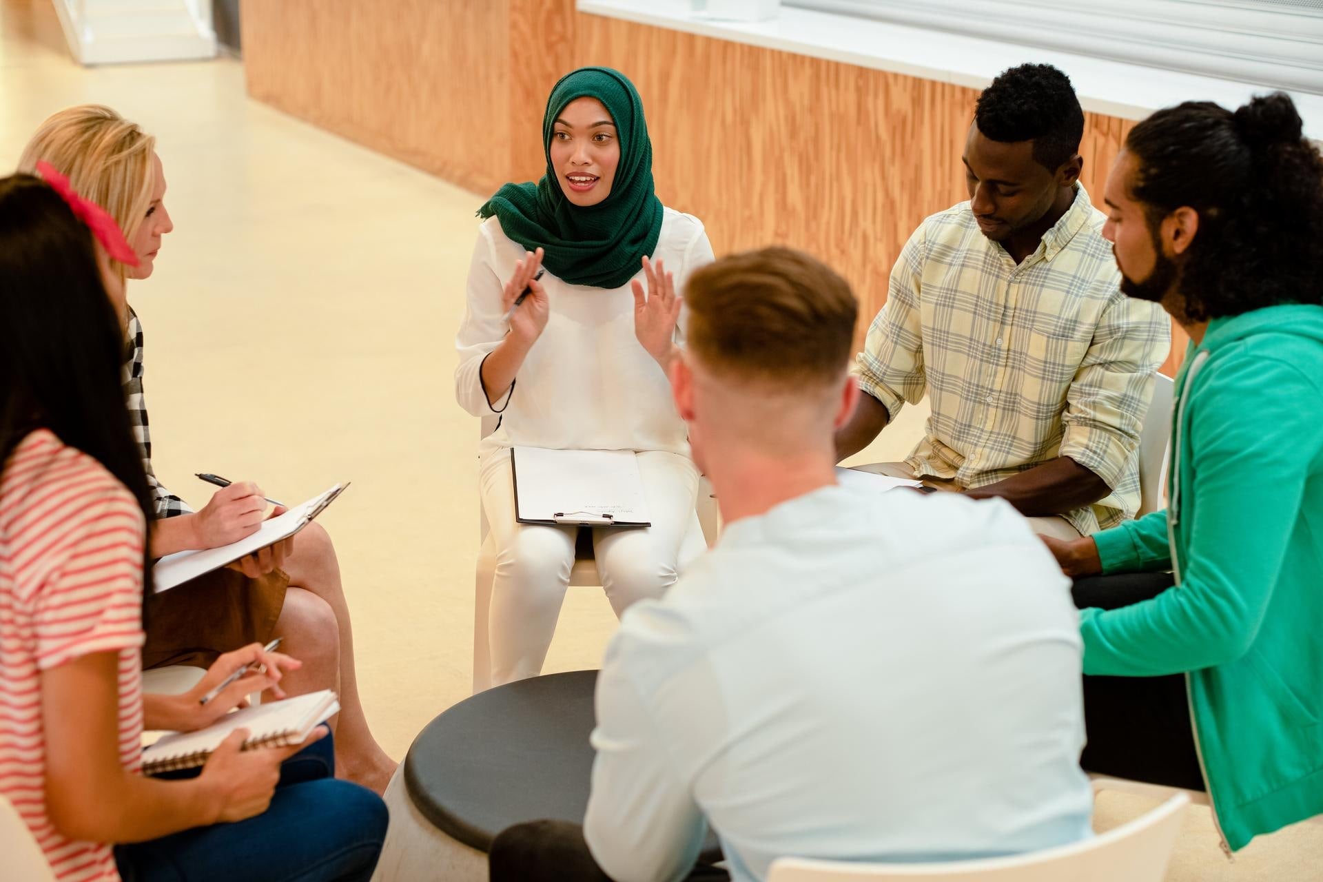 Group of people with multicultural background sitting together and speaking Finnish language in YKI Speaking Club.