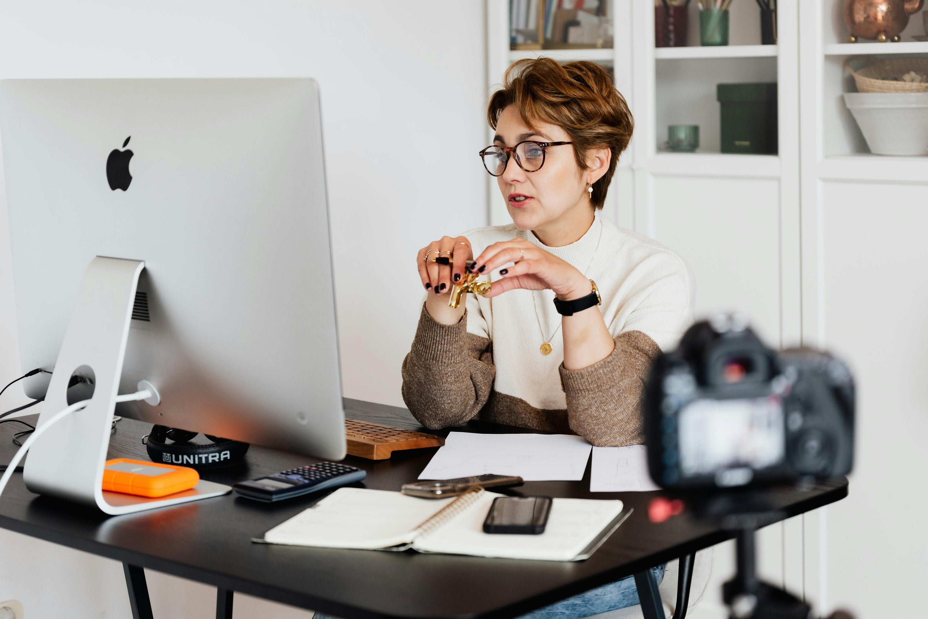 A woman with short hair and glasses taking online class for preparing for the YKI test. She is sitting infront of a desktop computer. 